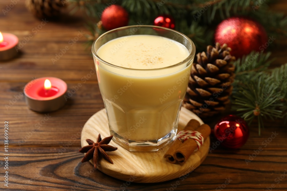 Tasty Christmas cocktail (eggnog) in glass, festive decor and burning candles on wooden table, closeup Tasty Christmas cocktail (eggnog) in glass, festive decor and burning candles on wooden table, closeup