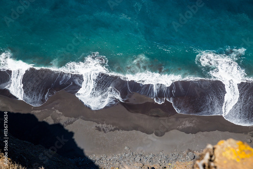 Spiaggia nera bagnata da onde vista dall'alto photo