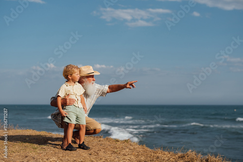 Grandfather and grandson bonding on a peaceful beach, enjoying the view of the ocean and creating lasting memories on a summer day