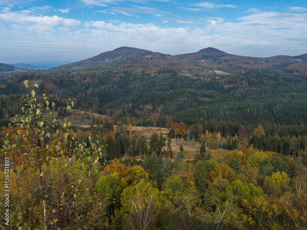 Panoramic view from viewpoint Stredni vrch near Dolni Prysk, Ceska Kamenice. Autumn landscape with colorful forest, hills and blue cloudy sky in Luzicke hory Lusatian Mountains, Czech Republic. Panoramic view from viewpoint Stredni vrch near Dolni Prysk, Ceska Kamenice. Autumn landscape with colorful forest, hills and blue cloudy sky in Luzicke hory Lusatian Mountains, Czech Republic.