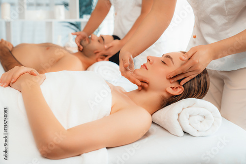 Caucasian couple enjoying relaxing anti-stress head massage and pampering facial beauty skin recreation leisure in dayspa modern light ambient at luxury resort or hotel spa salon. Quiescent photo