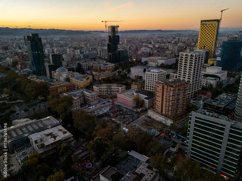 Obraz premium Aerial view of Tirana, Albania, showcasing modern architecture and urban landscape at sunset with mountains in the background.