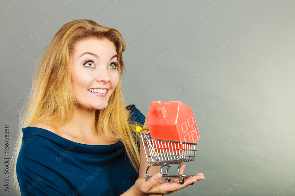 Woman holding shopping cart with house inside Woman holding shopping cart with house inside