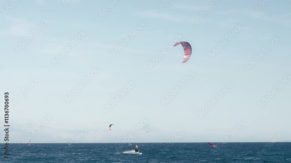 Kitesurfers catch the wind and surf the sea waves on kites and kiteboards along Zlatni Rat beach on the island Brac (Brač), Croatia. Extreme water sports. Summer tourist season on the Adriatic coast. Kitesurfers catch the wind and surf the sea waves on kites and kiteboards along Zlatni Rat beach on the island Brac (Brač), Croatia. Extreme water sports. Summer tourist season on the Adriatic coast.