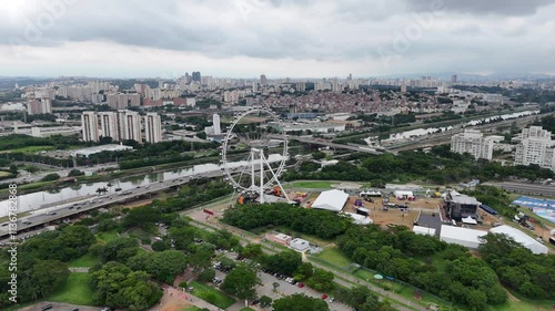 Vídeo aéreo em 4K de uma roda-gigante no Parque Villa Lobos, próximo à Marginal Pinheiros, em São Paulo, destacando áreas verdes e a movimentação urbana ao redor