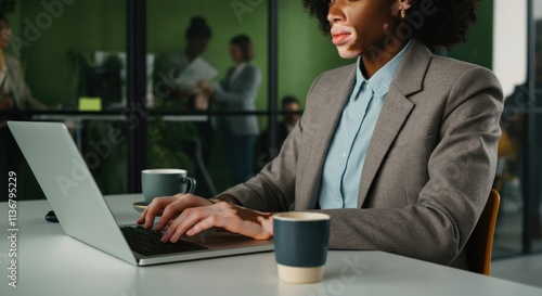 Professional african female working on laptop in modern office environment