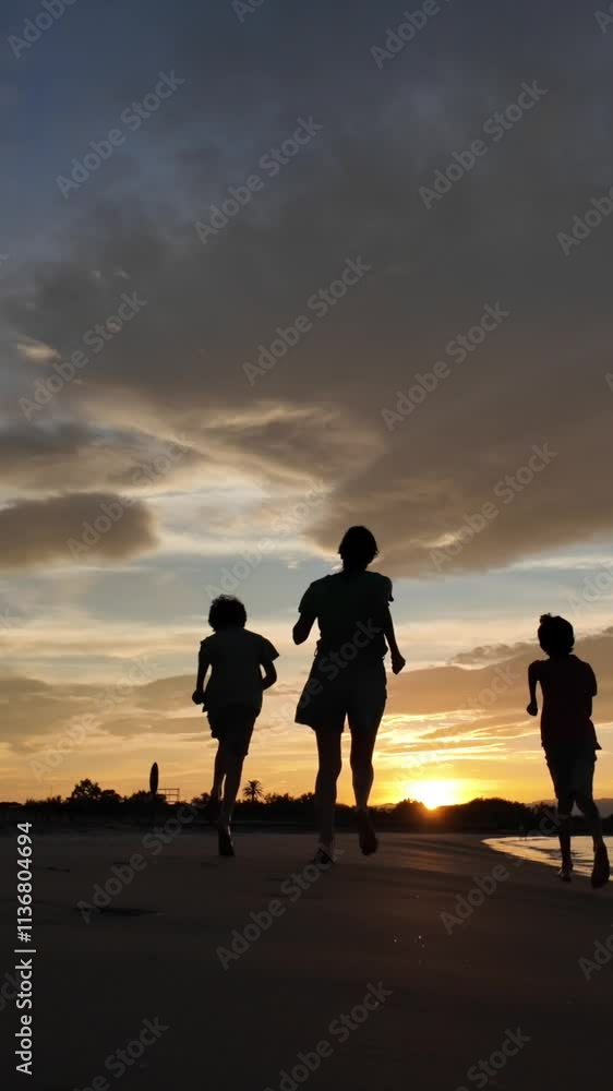 Two children and mother jumping on a beach silhouetted against a sunset. Dynamic movement and vibrant colors. Concept: freedom and joy. Two children and mother jumping on a beach silhouetted against a sunset. Dynamic movement and vibrant colors. Concept: freedom and joy.