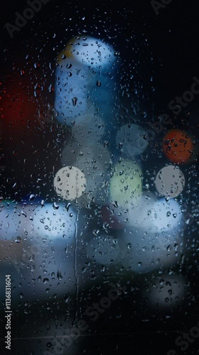 Raindrops on a window close-up against a blurred night city background.