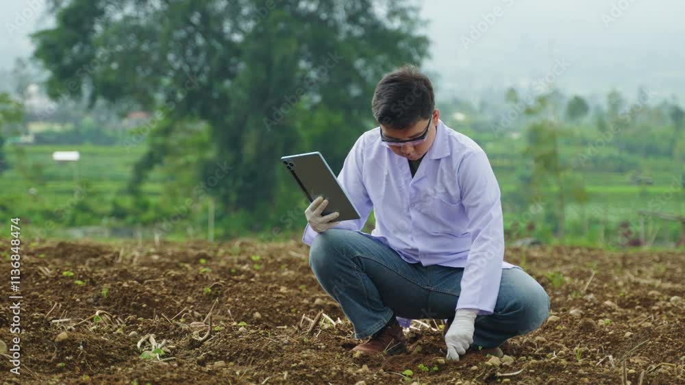 Young Scientist Using Technology to Check Soil Quality, Documenting Fertility Data with Tablet for Efficient Planting Process. Agronomists Checking Soil Quality in Fields Young Scientist Using Technology to Check Soil Quality, Documenting Fertility Data with Tablet for Efficient Planting Process. Agronomists Checking Soil Quality in Fields
