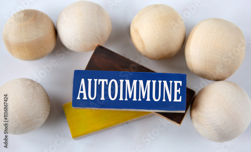 AUTOIMMUNE - word on a wooden brown block with balls lying next to it on a white background photo