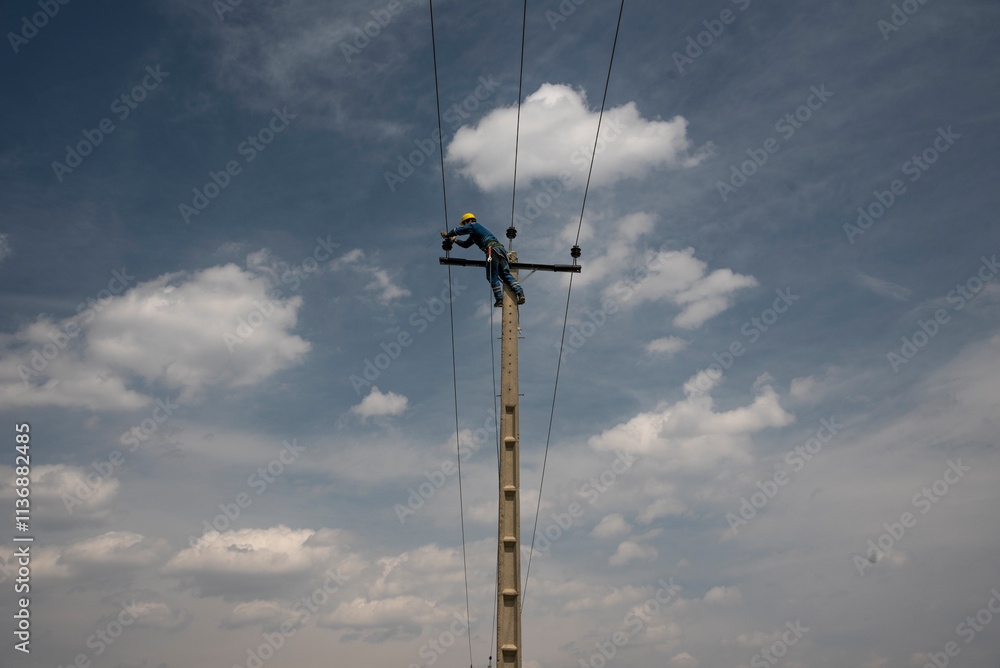 Man Working on Electric Pole, Replacing Power Cables High Above the Ground Man Working on Electric Pole, Replacing Power Cables High Above the Ground
