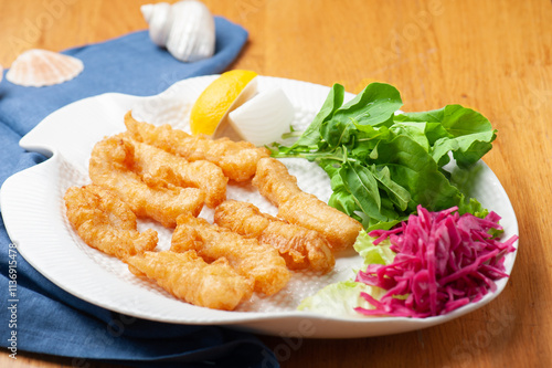 A beautiful presentation of fried cuttlefish with, lemon, arugula and pickled red cabbage on the side