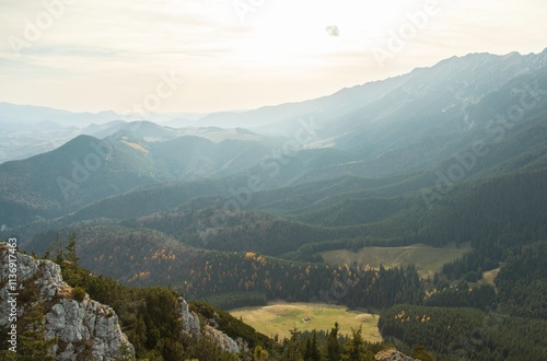 Expansive views of a mountainous region captured during golden hour, showcasing lush green valleys and rocky outcrops under a serene sky photo