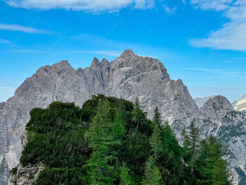 Hiking trail with scenic view of rugged mountain peak Jalovec and Prisank in Julian Alps seen from Triglav National Park, Vrsic pass, Slovenia. Wanderlust wild Slovenian Alps. Sharp steep ridges Hiking trail with scenic view of rugged mountain peak Jalovec and Prisank in Julian Alps seen from Triglav National Park, Vrsic pass, Slovenia. Wanderlust wild Slovenian Alps. Sharp steep ridges