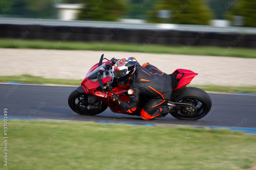 Fototapeta premium Motorcycle rider on a red sport bike riding fast through a corner
