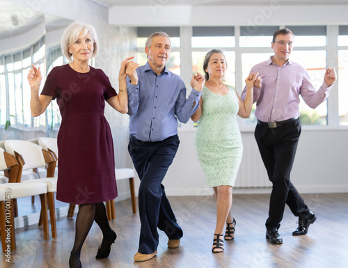 Group men and women dancing folk dance in row in studio photo