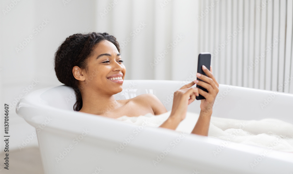 A woman sits comfortably in a cozy bathtub filled with bubbles, smiling as she uses her smartphone. The warm atmosphere promotes relaxation and self-care. A woman sits comfortably in a cozy bathtub filled with bubbles, smiling as she uses her smartphone. The warm atmosphere promotes relaxation and self-care.
