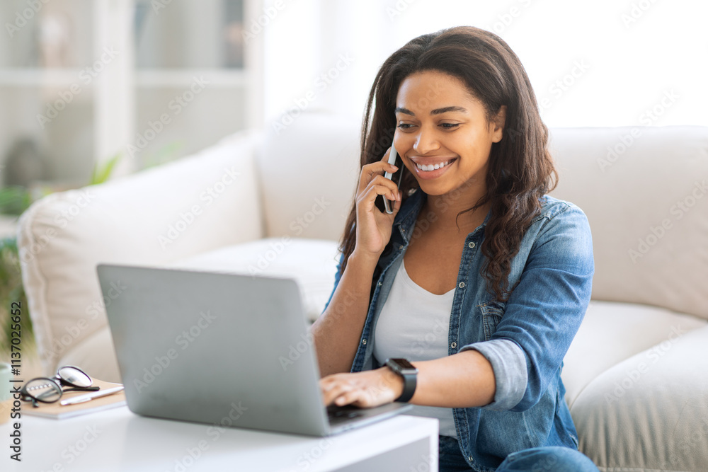 A young woman sits comfortably in a bright living room, smiling as she works on her laptop and talks on the phone. The cozy atmosphere is enhanced by natural light and modern decor elements. A young woman sits comfortably in a bright living room, smiling as she works on her laptop and talks on the phone. The cozy atmosphere is enhanced by natural light and modern decor elements.