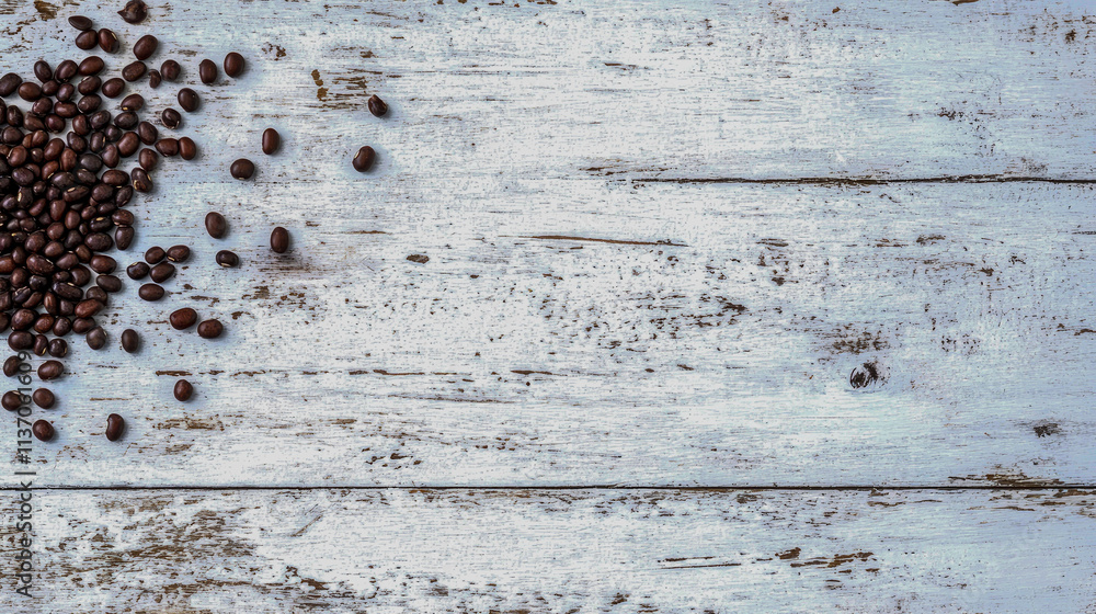 Fototapeta premium Coffee beans scattered on rustic wood.