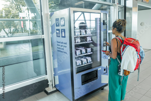 Traveler using vending machine for masks at airport terminal