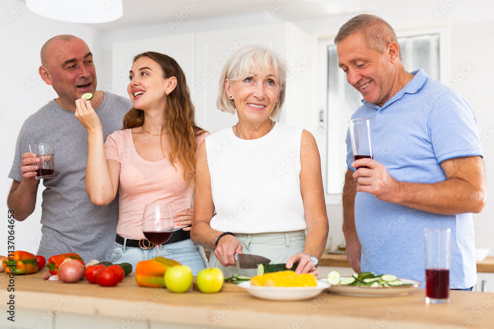 Friendly family of four is preparing a festive dinner in the kitchen of the house, holding glasses of wine in their hands Friendly family of four is preparing a festive dinner in the kitchen of the house, holding glasses of wine in their hands