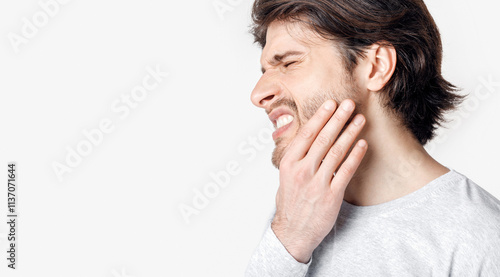 Not tolerate pain in teeth and dentures. Man suffers from pain and presses his hand to cheek, panorama, cropped, studio shot