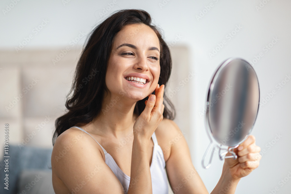 Brunette woman smiles at her reflection while applying skincare product in a serene, sunny bathroom. This moment captures the essence of self-care and beauty rituals at home. Brunette woman smiles at her reflection while applying skincare product in a serene, sunny bathroom. This moment captures the essence of self-care and beauty rituals at home.