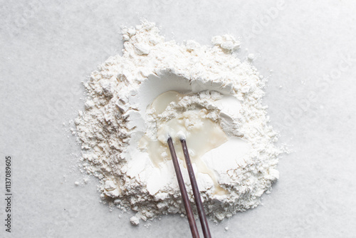 Overhead view of scallion pancake dough being made on a marble countertop, top view of cong you bing dough being mixed with chopsticks, process of making scallion pancakes photo