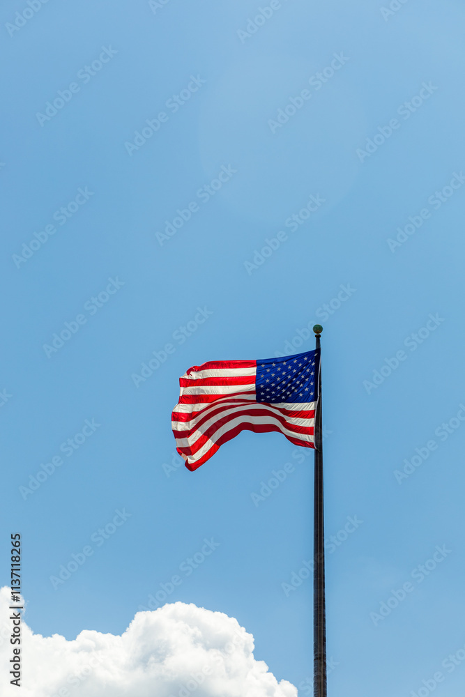 A red, white, and blue American flag is flying high in the sky A red, white, and blue American flag is flying high in the sky