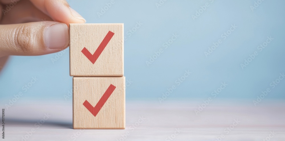 Hand Holding Wooden Blocks With Check Marks on Soft Blue Background Hand Holding Wooden Blocks With Check Marks on Soft Blue Background