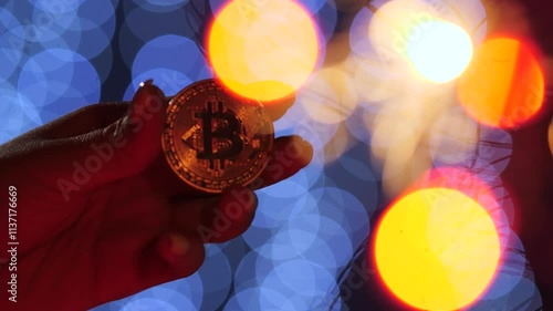 Vertical video of a bitcoin coin in a woman's hand against the backdrop of Christmas lights.