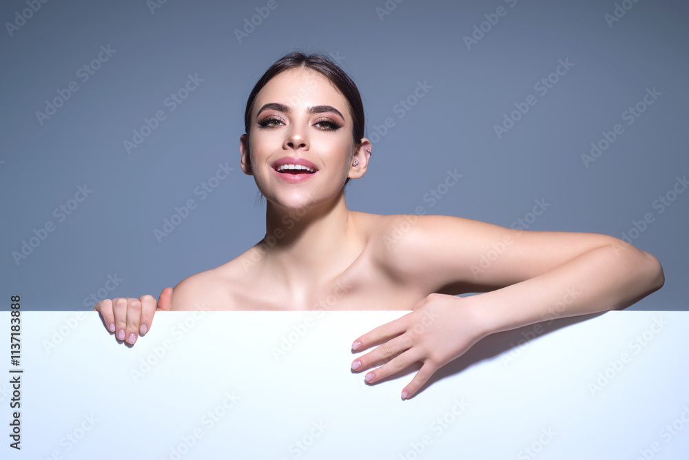 Beautiful woman showing a board. Woman pointing at the board. Woman holding blank card. Promo advertising. Presenting something on white blank board with empty space. Presents blank board.