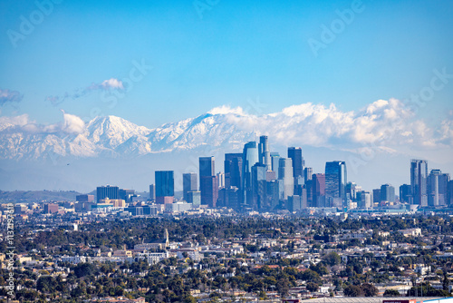 View over Los Angeles Skyline in California with snow covered mountains in the background. Visible are San Gabriel and San Bernardino mountains. 