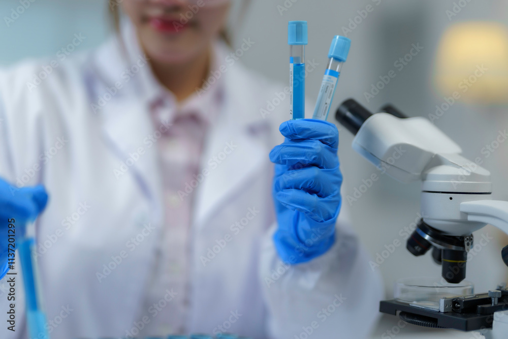 Scientist wearing blue gloves holding two test tubes with blue liquid conducting research in a laboratory Scientist wearing blue gloves holding two test tubes with blue liquid conducting research in a laboratory