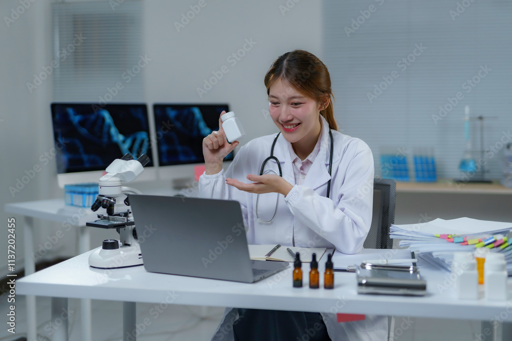 Young scientist having video call and showing medicine bottle while working at modern laboratory Young scientist having video call and showing medicine bottle while working at modern laboratory