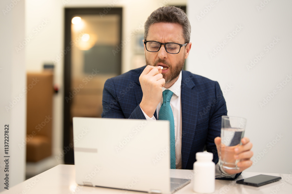 Man taking a medicine pill from headache migraine. Tired businessman is working overtime and has headache. Man with laptop at workplace, suffers from headache. Migraine from overwork, deadline. Man taking a medicine pill from headache migraine. Tired businessman is working overtime and has headache. Man with laptop at workplace, suffers from headache. Migraine from overwork, deadline.