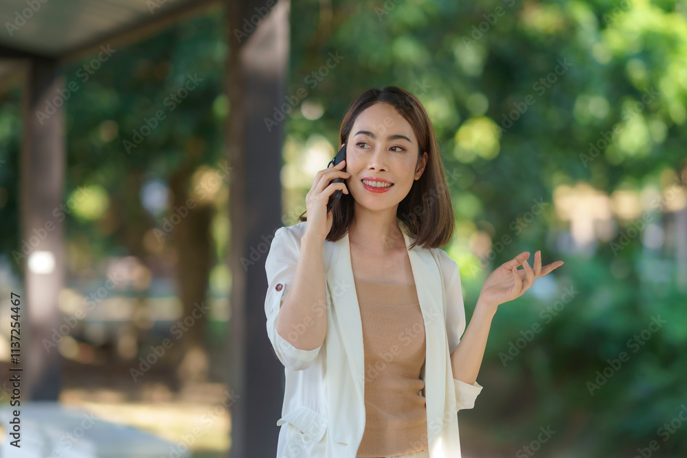 Young businesswoman is using her phone in a park, gesturing while speaking, indicating active engagement in her conversation Young businesswoman is using her phone in a park, gesturing while speaking, indicating active engagement in her conversation