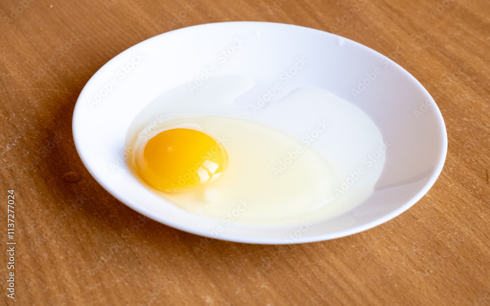 Raw egg in a plate on the table.Preparing breakfast. Raw egg in a plate on the table.Preparing breakfast.