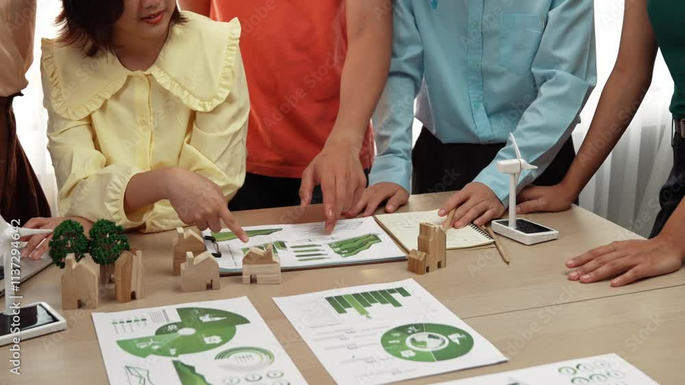 Business team consulting and analyzing green power graph usage for future esg of company. Windmill model represented using clean energy and house block symbolized eco house on the table. Delineation. Business team consulting and analyzing green power graph usage for future esg of company. Windmill model represented using clean energy and house block symbolized eco house on the table. Delineation.