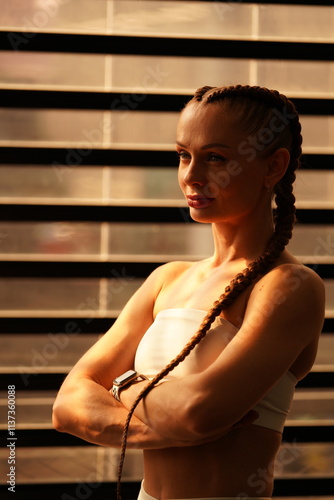 Confident fitness model posing in gym with weightlifting equipment in background