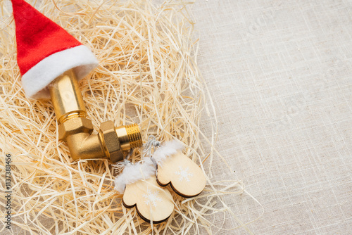 Christmas decoration, brass hydraulic connectors and bright steel snakes, against the background of a red hat and hay photo