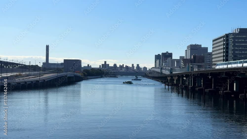 A calm riverside view in Tokyo, Japan, with highways, buildings, and blue skies A calm riverside view in Tokyo, Japan, with highways, buildings, and blue skies
