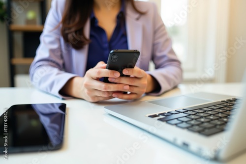 Focused Businesswoman Using Smartphone and Laptop in Modern Office Setting, Ideal for Productivity and Technology Themed Content