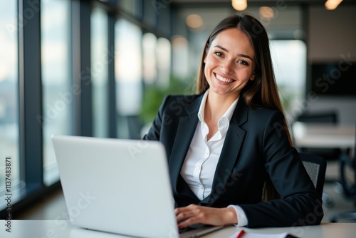 Professional Business Woman Smiling at Laptop in Modern Office Setting, Perfect for Business Marketing or Inspirational Content