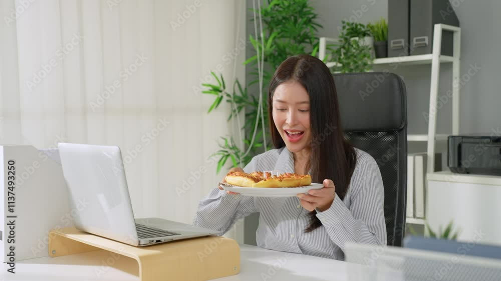 Asian young businesswoman eating homemade pizza while working in office. Asian young businesswoman eating homemade pizza while working in office.
