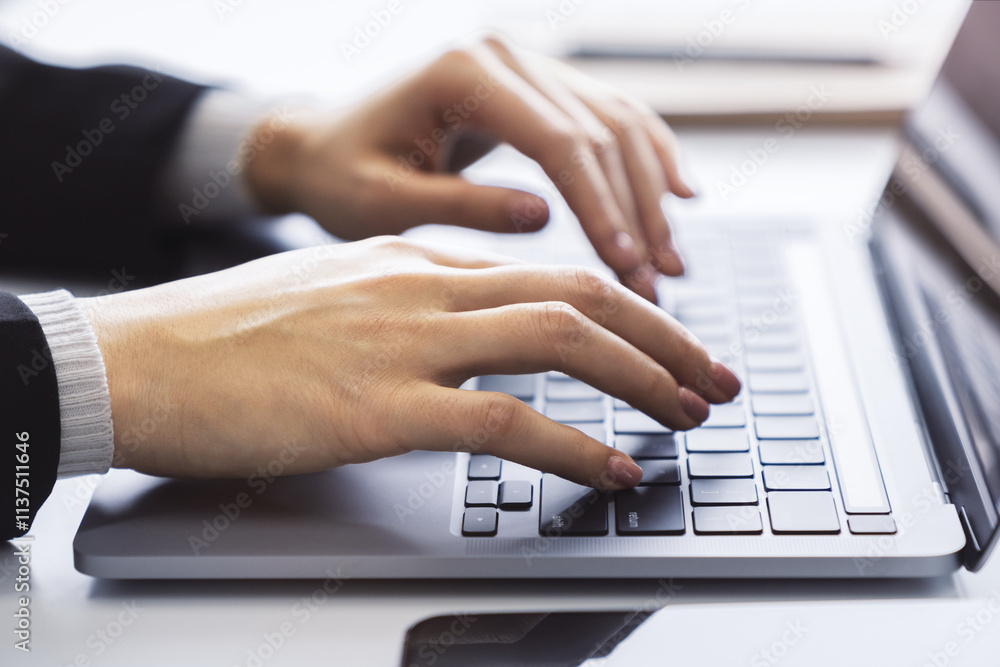 With a blurred office environment in the backdrop, the image focuses on a woman's hands typing on a state-of-the-art laptop keyboard With a blurred office environment in the backdrop, the image focuses on a woman's hands typing on a state-of-the-art laptop keyboard