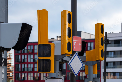 The image features bright yellow traffic lights and a red sign at a city intersection, emphasizing urban traffic management and safety in busy environments. photo