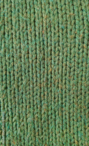 green Wool fabric photographed close-up in a special design. Texture faded material. Clothing background sweater