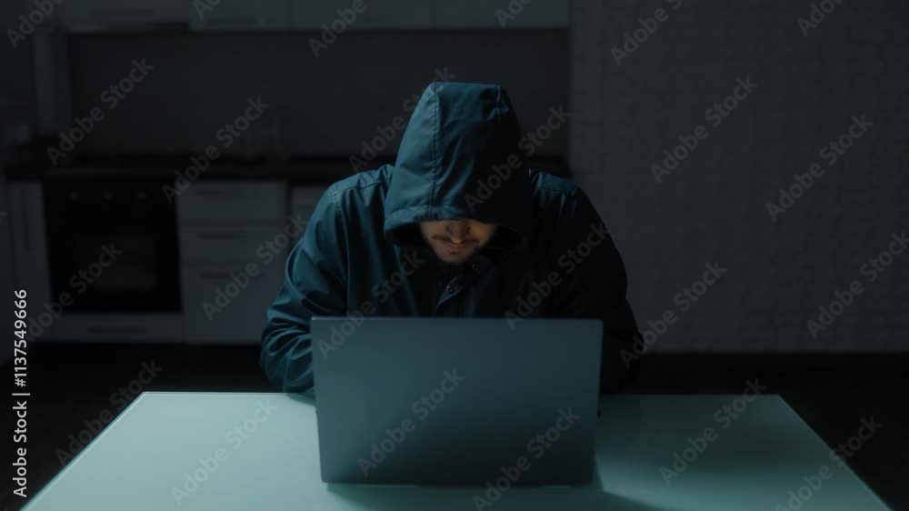 Cybersecurity Scene Hooded Man Focused on Laptop at Home Kitchen Cybersecurity Scene Hooded Man Focused on Laptop at Home Kitchen