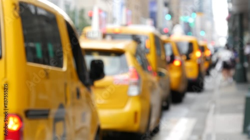 New York City. Row of yellow taxi cars on Manhattan street. Many taxi cabs on Midtown 8th avenue. Medallion taxicab in line near Penn Station waiting for passengers. Defocused urban scene, pedestrians